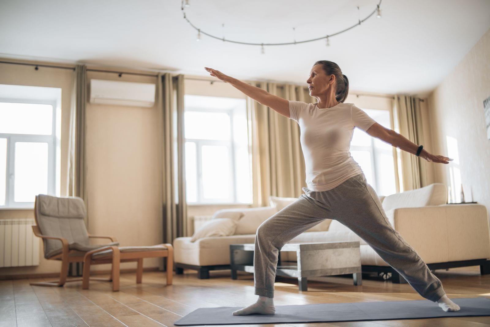 Mujer de 40+ entrenando con fuerza y seguridad en su sala de casa